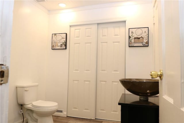 bathroom with toilet, vanity, ornamental molding, and hardwood / wood-style flooring