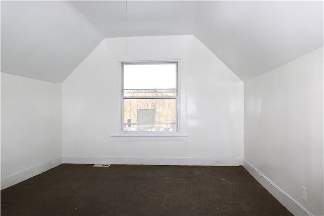 bonus room with vaulted ceiling and dark colored carpet