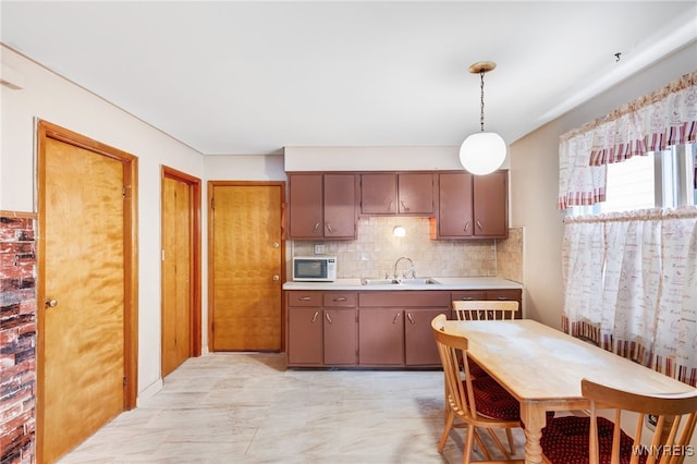 kitchen featuring tasteful backsplash, dark brown cabinetry, sink, and pendant lighting