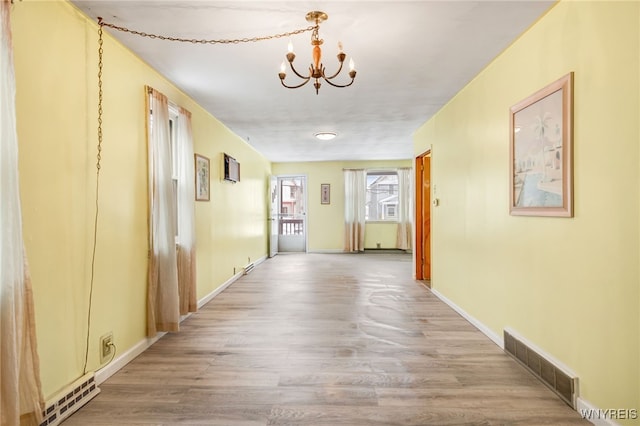 hallway with a chandelier and hardwood / wood-style floors