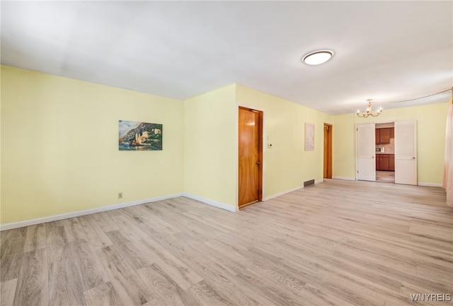 unfurnished room featuring light wood-type flooring and a chandelier