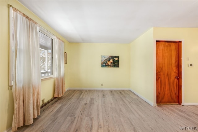 empty room featuring a baseboard heating unit and light wood-type flooring