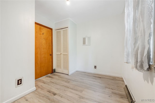 unfurnished room with light wood-type flooring and baseboard heating