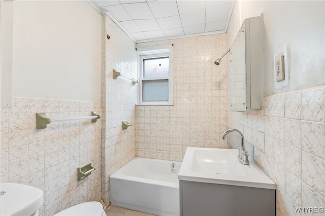 full bathroom with toilet, vanity, tile walls, and tiled shower / bath