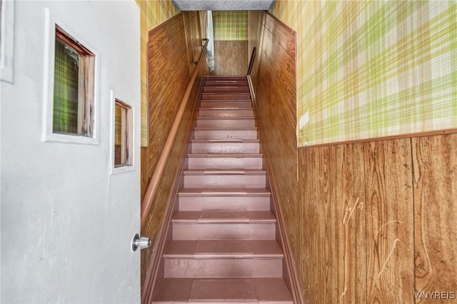 stairway featuring tile patterned floors and wooden walls