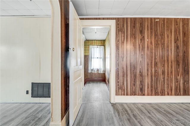 hallway with wood-type flooring and wooden walls