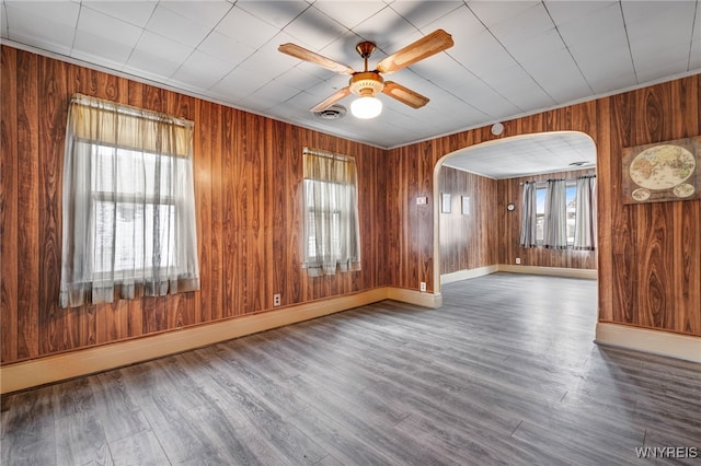 empty room with a baseboard heating unit, ceiling fan, and a wealth of natural light