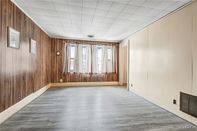 unfurnished room featuring light hardwood / wood-style flooring and wooden walls