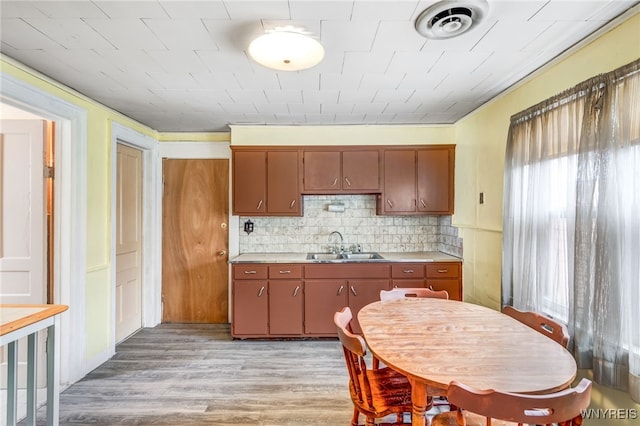 kitchen featuring backsplash, sink, crown molding, and light hardwood / wood-style floors