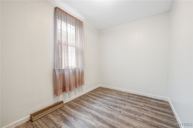 unfurnished room with a baseboard heating unit and hardwood / wood-style flooring