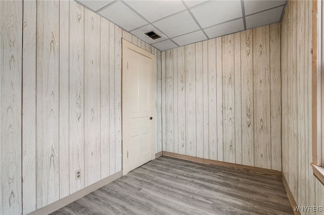 spare room featuring a drop ceiling and light hardwood / wood-style floors