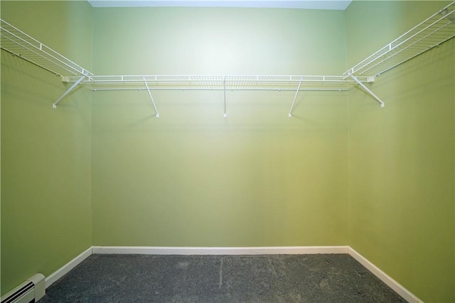 spacious closet featuring a baseboard heating unit and carpet