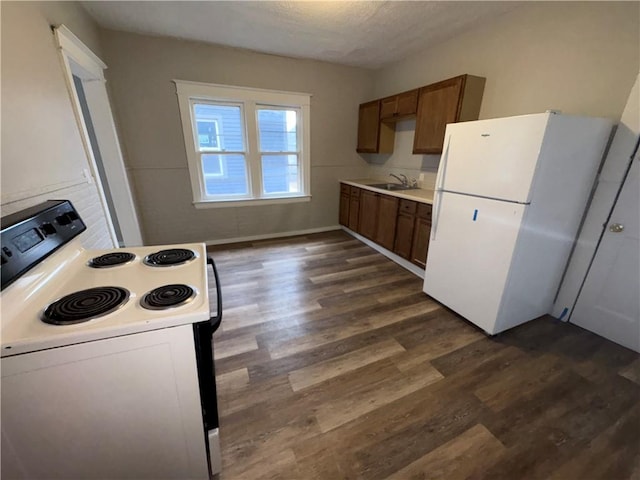 kitchen featuring dark wood-type flooring, sink, white appliances, and a textured ceiling