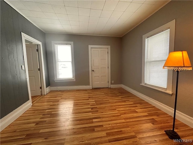 spare room with light wood-type flooring and wood walls