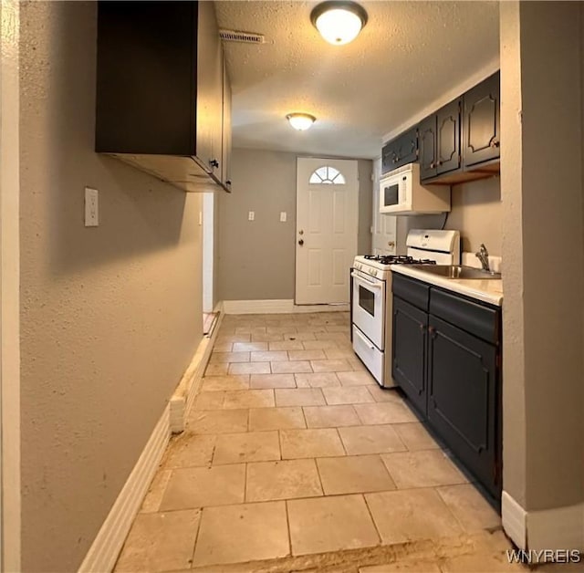 kitchen with light tile patterned floors, sink, white appliances, and a textured ceiling