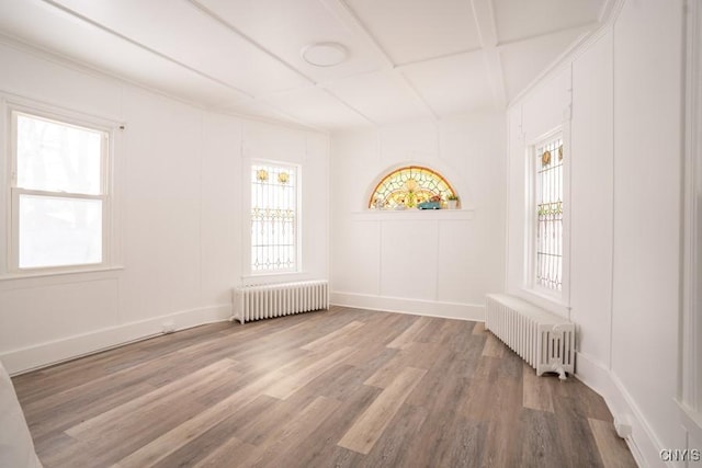 spare room featuring radiator, coffered ceiling, and hardwood / wood-style flooring