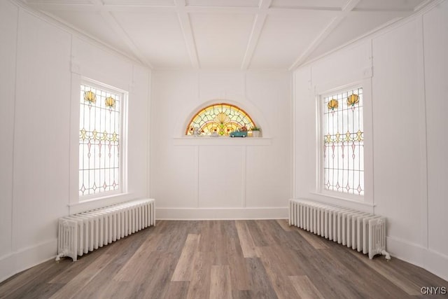 spare room with hardwood / wood-style floors, radiator, beamed ceiling, and coffered ceiling