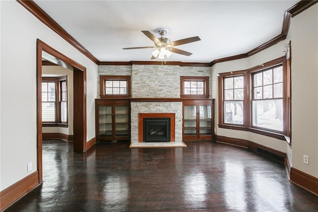 unfurnished living room featuring ornamental molding, a healthy amount of sunlight, and a stone fireplace