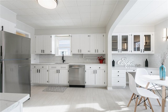 kitchen featuring sink, backsplash, white cabinets, and stainless steel appliances