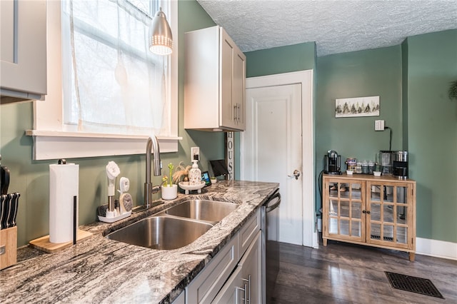 kitchen with light stone countertops, a textured ceiling, white cabinets, dishwasher, and sink