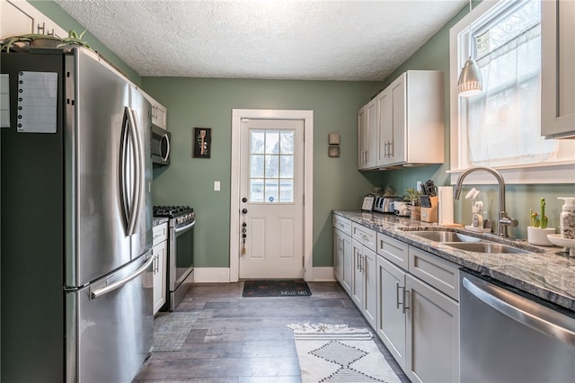 kitchen with white cabinetry, stainless steel appliances, light stone countertops, a textured ceiling, and sink