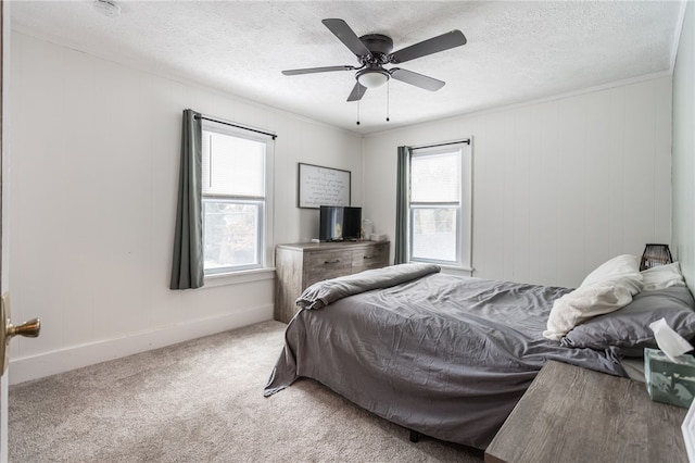 bedroom featuring ceiling fan, multiple windows, a textured ceiling, and carpet flooring