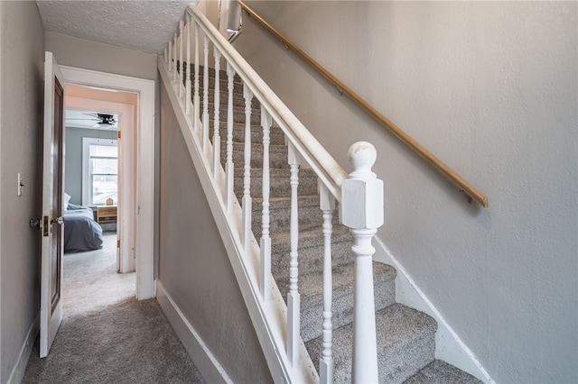 stairway with carpet floors and a textured ceiling