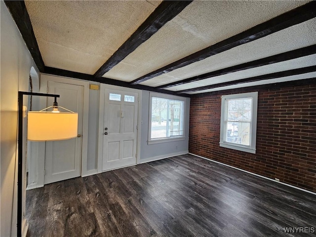 entryway featuring a textured ceiling, brick wall, a healthy amount of sunlight, and beamed ceiling