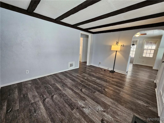 spare room featuring dark hardwood / wood-style flooring and beamed ceiling