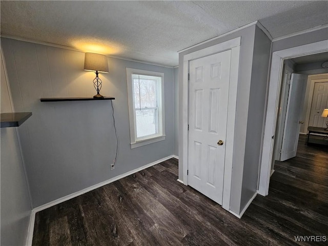 interior space featuring a textured ceiling, a closet, dark hardwood / wood-style flooring, and crown molding