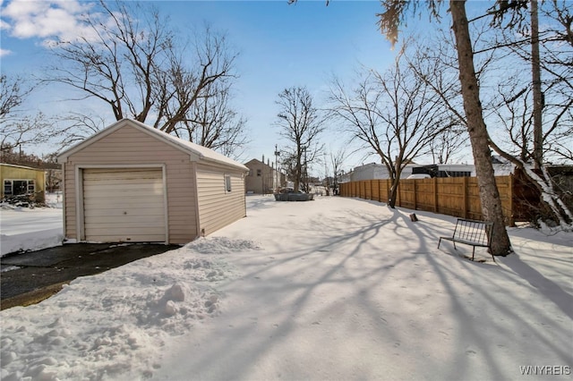 yard layered in snow with a garage and an outbuilding