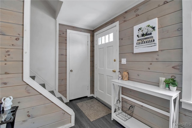 foyer entrance with dark hardwood / wood-style flooring and wooden walls