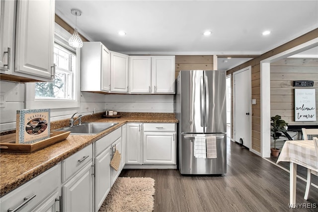 kitchen with dark wood-type flooring, stainless steel refrigerator, white cabinetry, and pendant lighting