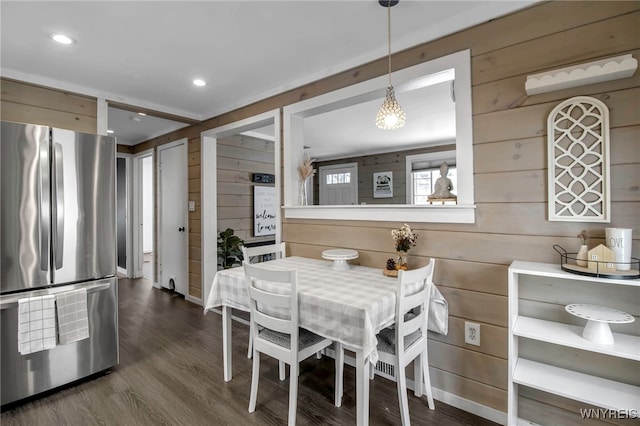 dining room featuring dark hardwood / wood-style floors and wooden walls