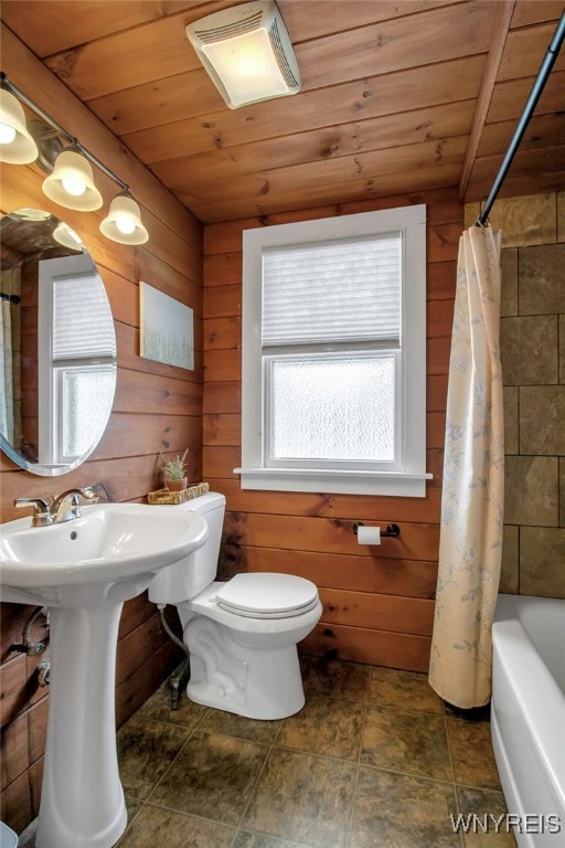 bathroom with toilet, wood walls, and wood ceiling