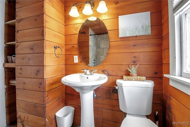 bathroom with toilet, sink, and wooden walls