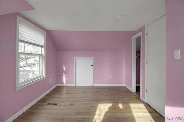 additional living space with light hardwood / wood-style floors and vaulted ceiling