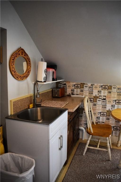 kitchen featuring sink, white cabinetry, and vaulted ceiling