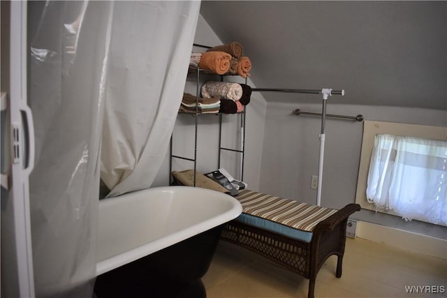 bathroom with a washtub and lofted ceiling