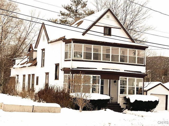 view of front of home featuring a garage, a sunroom, and an outdoor structure