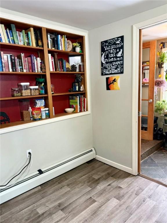 interior space featuring a baseboard heating unit and hardwood / wood-style flooring