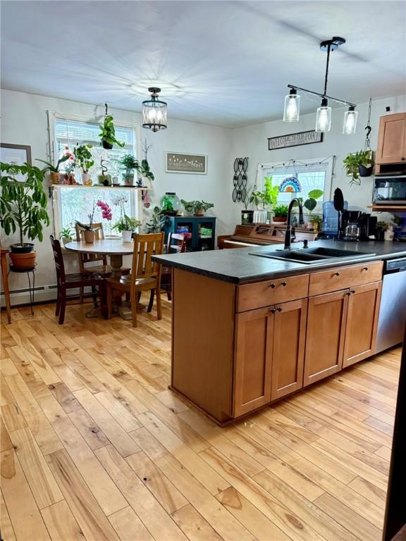 kitchen featuring a notable chandelier, light wood-type flooring, pendant lighting, stainless steel dishwasher, and sink