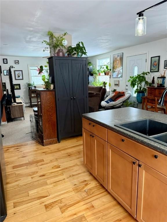 kitchen featuring decorative light fixtures, sink, and light hardwood / wood-style flooring