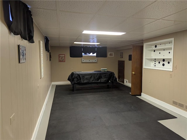 bedroom with a paneled ceiling and wooden walls