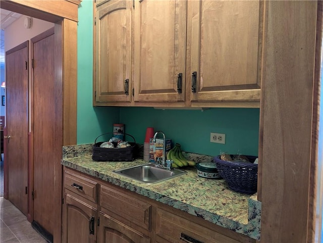 kitchen featuring light tile patterned floors, sink, and light stone counters