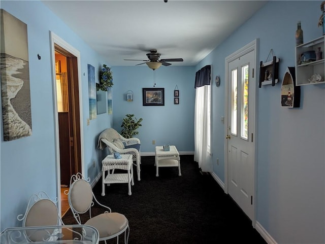 entryway with ceiling fan and dark colored carpet