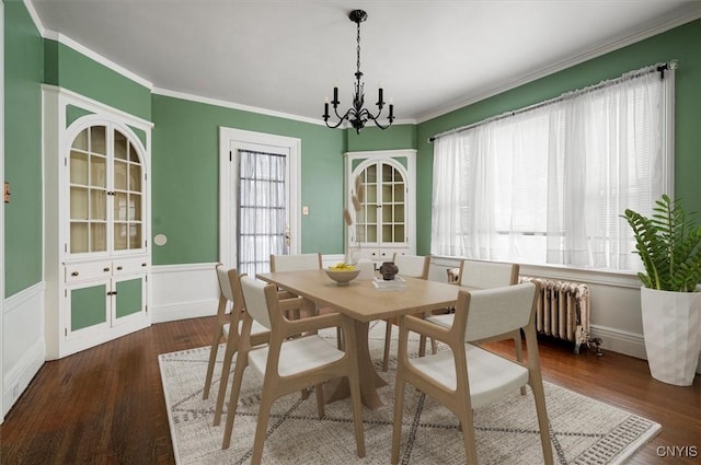 dining space with dark wood-type flooring, a chandelier, crown molding, and radiator heating unit