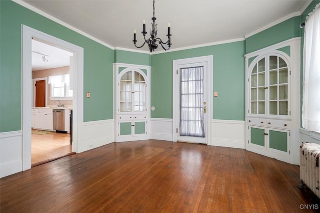 unfurnished dining area with a notable chandelier, sink, hardwood / wood-style floors, and radiator heating unit