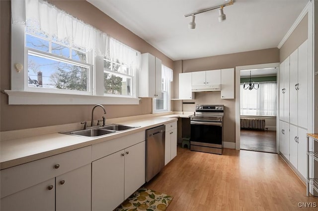 kitchen featuring white cabinets, appliances with stainless steel finishes, radiator, and sink