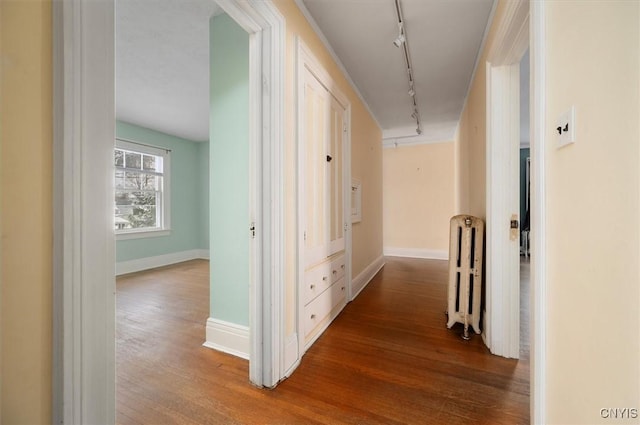 corridor featuring rail lighting, hardwood / wood-style flooring, and radiator heating unit